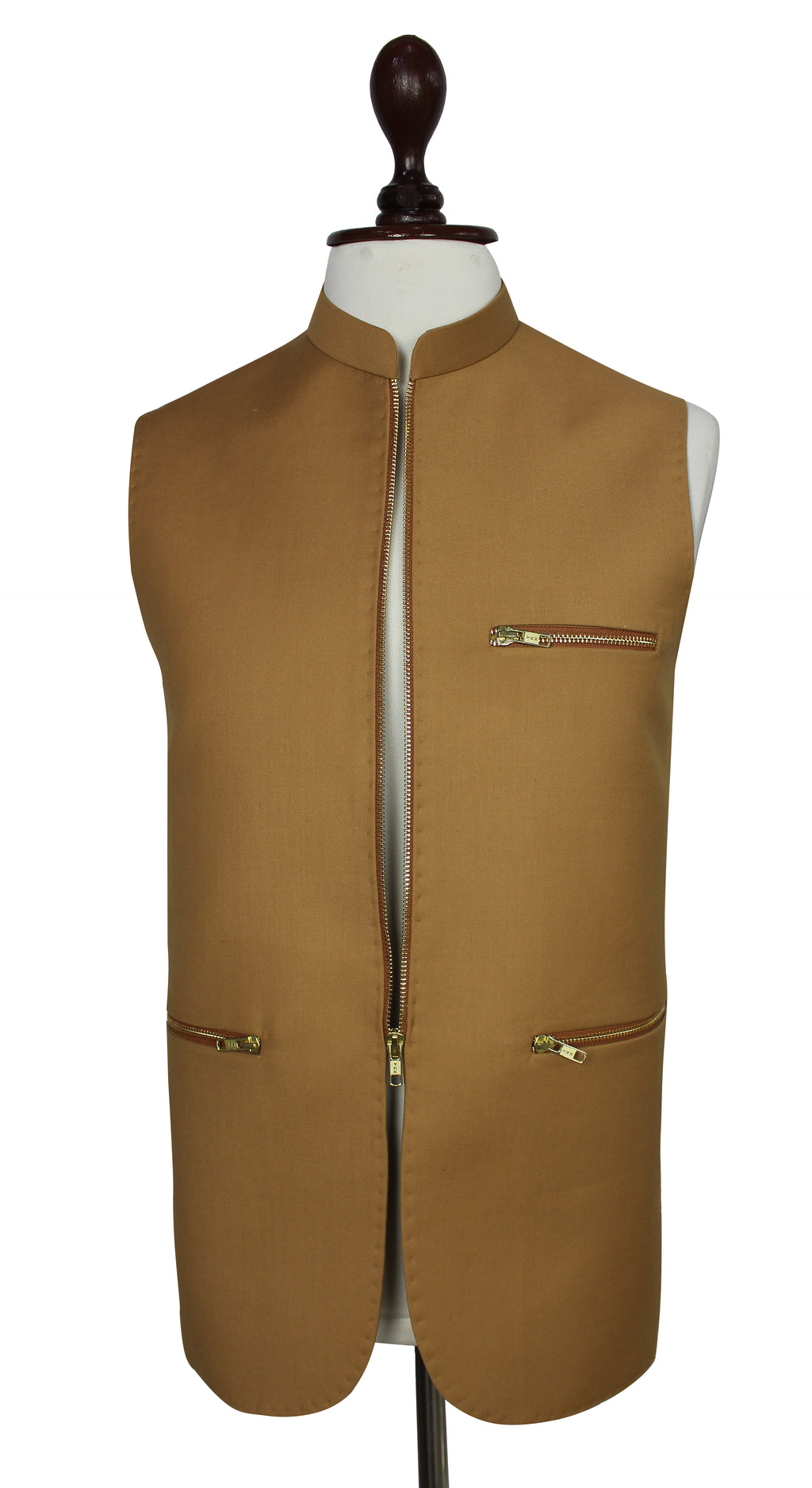 A tan waistcoat displayed on a white mannequin torso against a plain white background. The waistcoat features a mandarin collar, a front zipper closure, a zippered chest pocket, and two zippered lower pockets with gold-toned hardware.