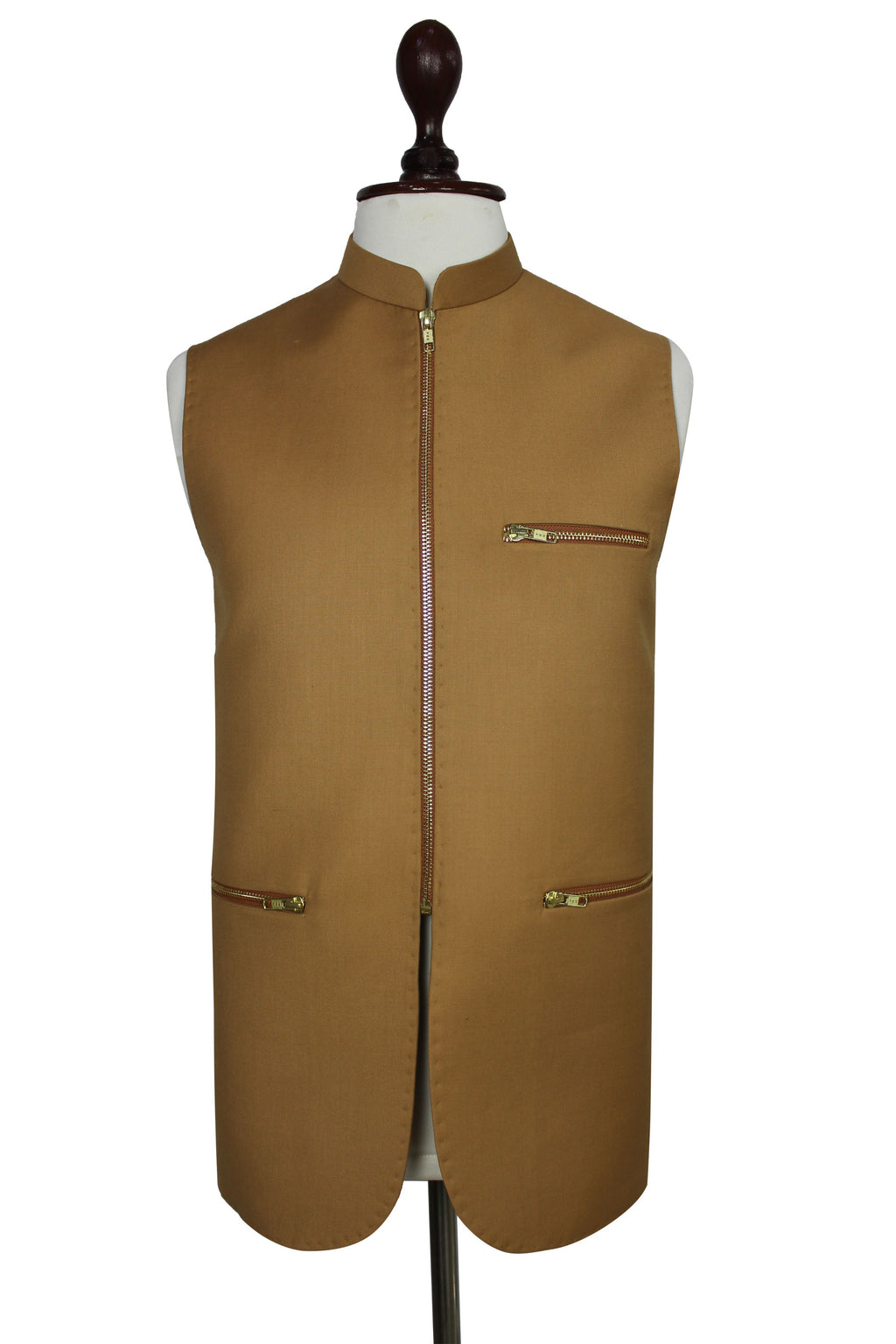 A sleeveless tan waistcoat displayed on a mannequin torso against a plain white background. The vest has a mandarin collar, a front zipper closure, two zippered chest pockets, and two zippered lower pockets, with a thin dark brown trim running down the center front.
